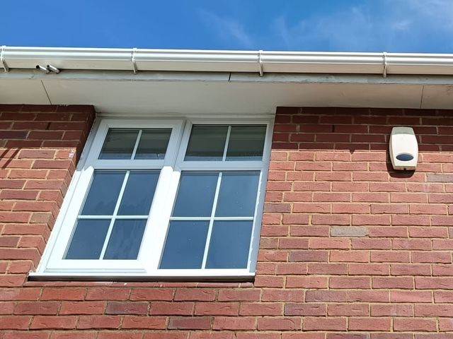 Clean white windows on a red brick house, the glass clear and the frames bright